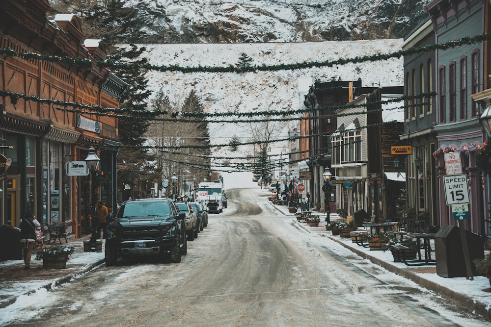 a snowy street with cars parked on the side of it