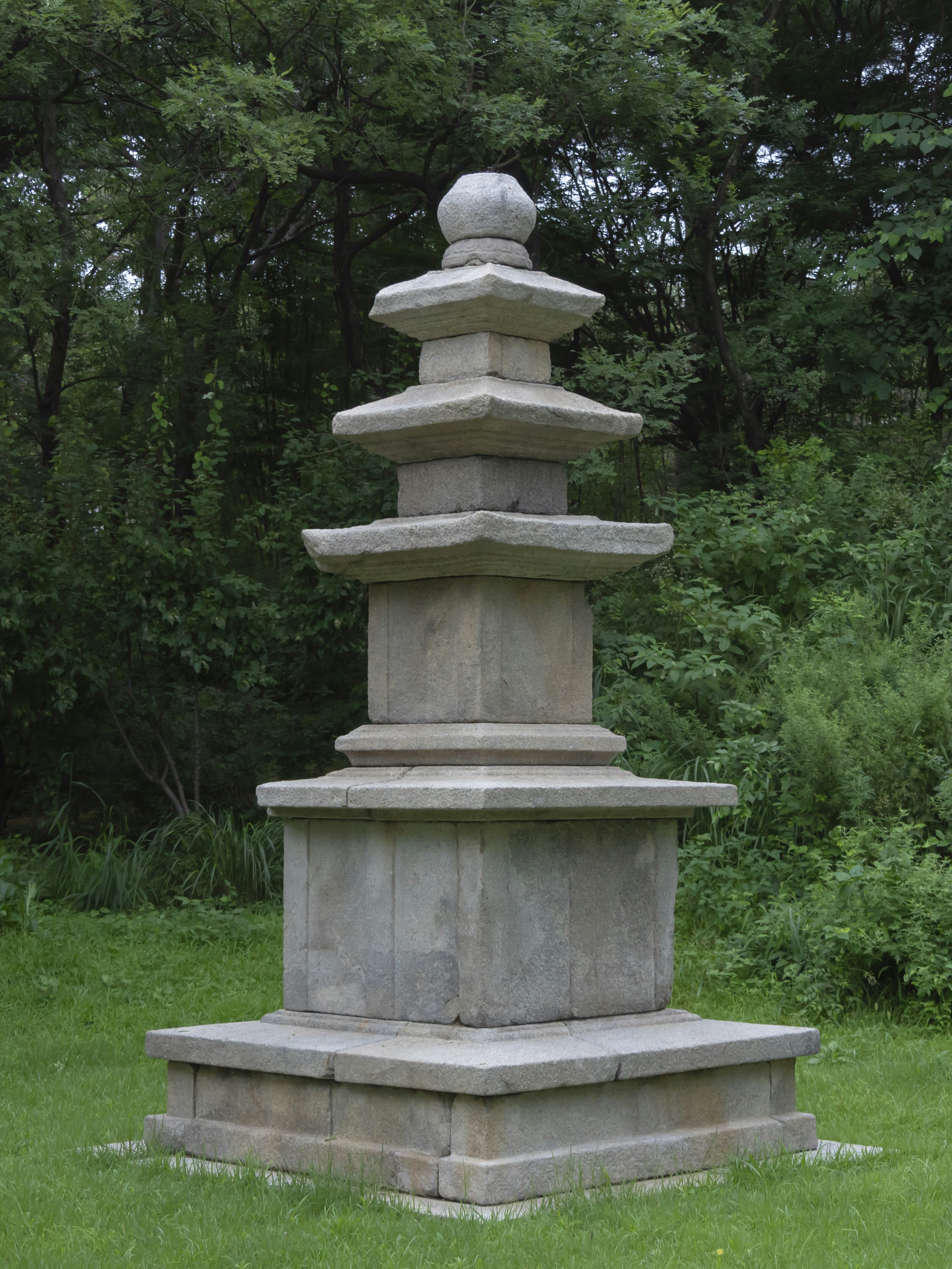 a stone tower sitting in the middle of a lush green field