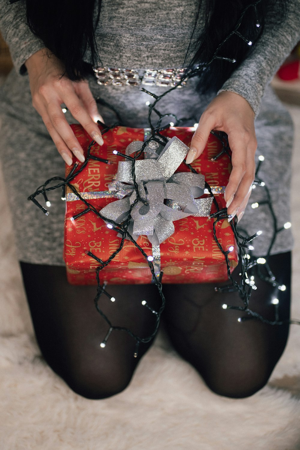 a woman holding a red present wrapped in string