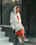 A model wearing a light, airy scarf styled casually against a minimalist white background