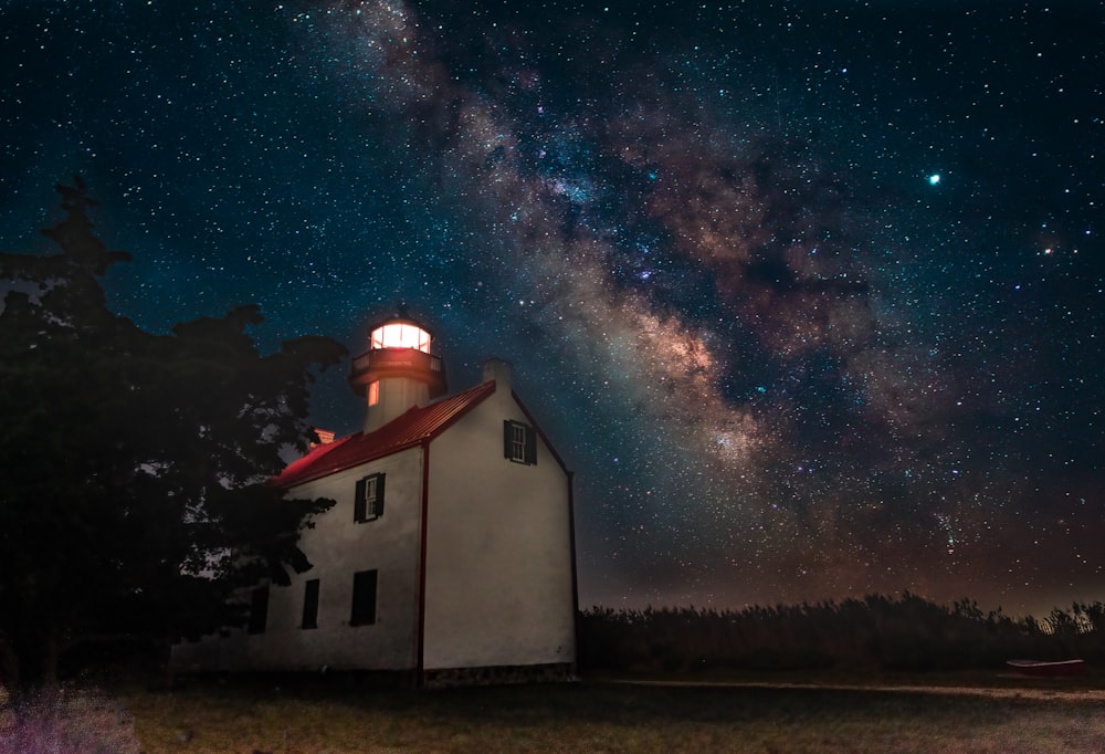 a white church with a red roof under a night sky filled with stars