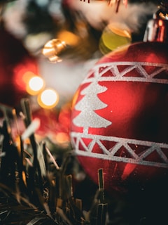 Close-up of a sparkling Christmas ornament with warm gold lighting and red accents.