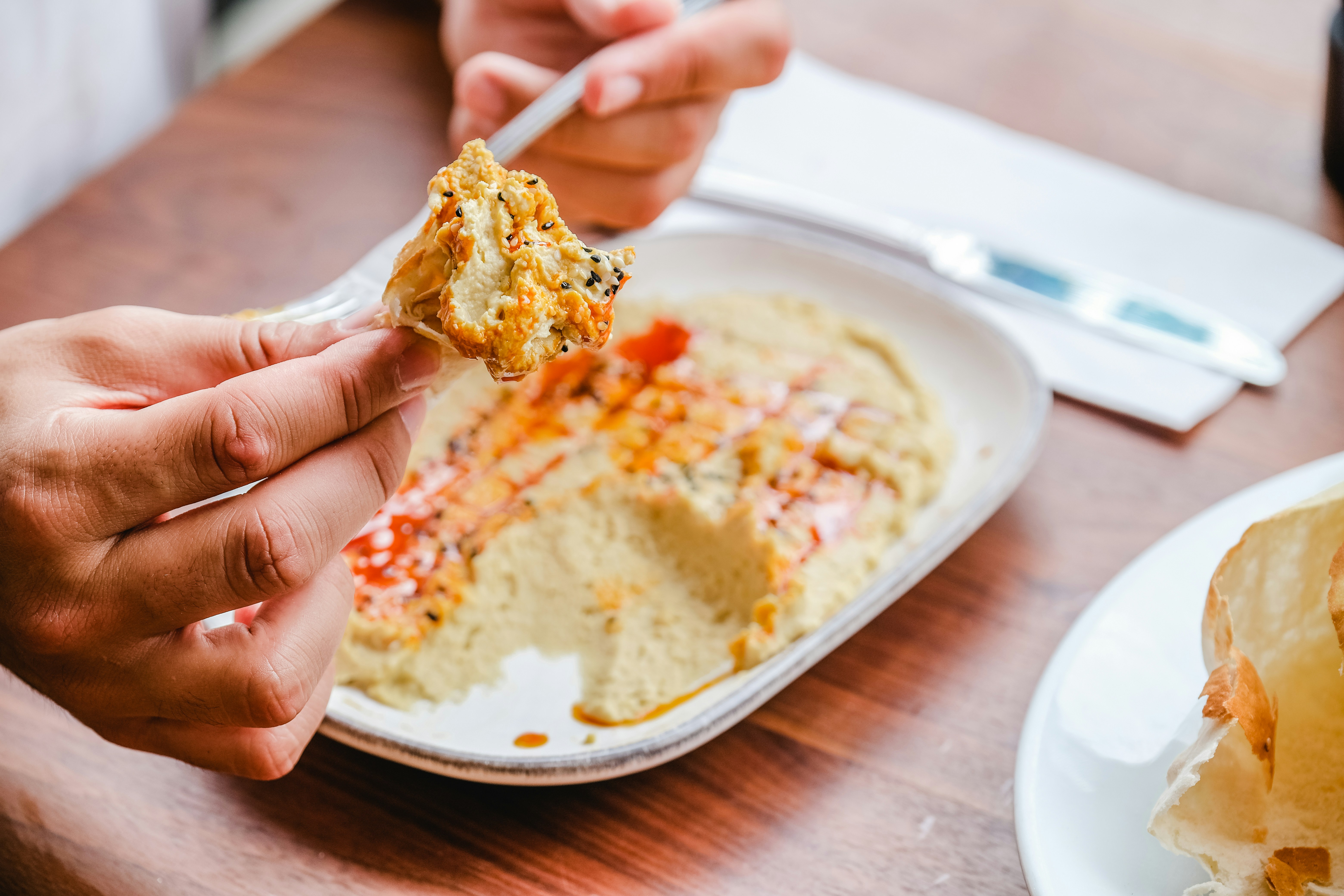A whole-wheat pita bread pocket filled with fresh vegetables and a generous spread of hummus