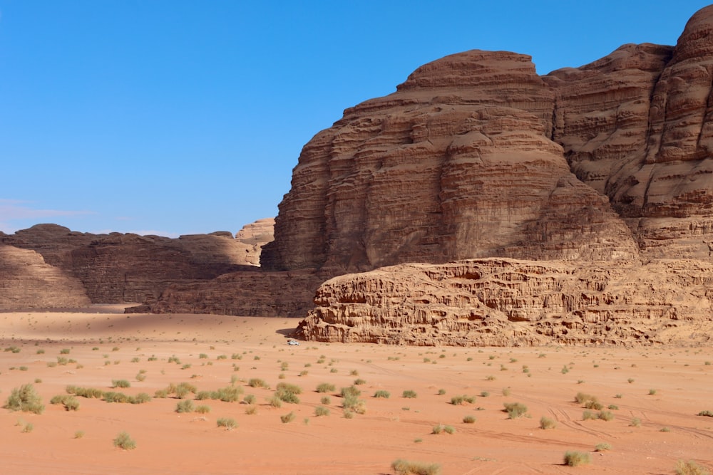 a desert scene with a rock formation in the background