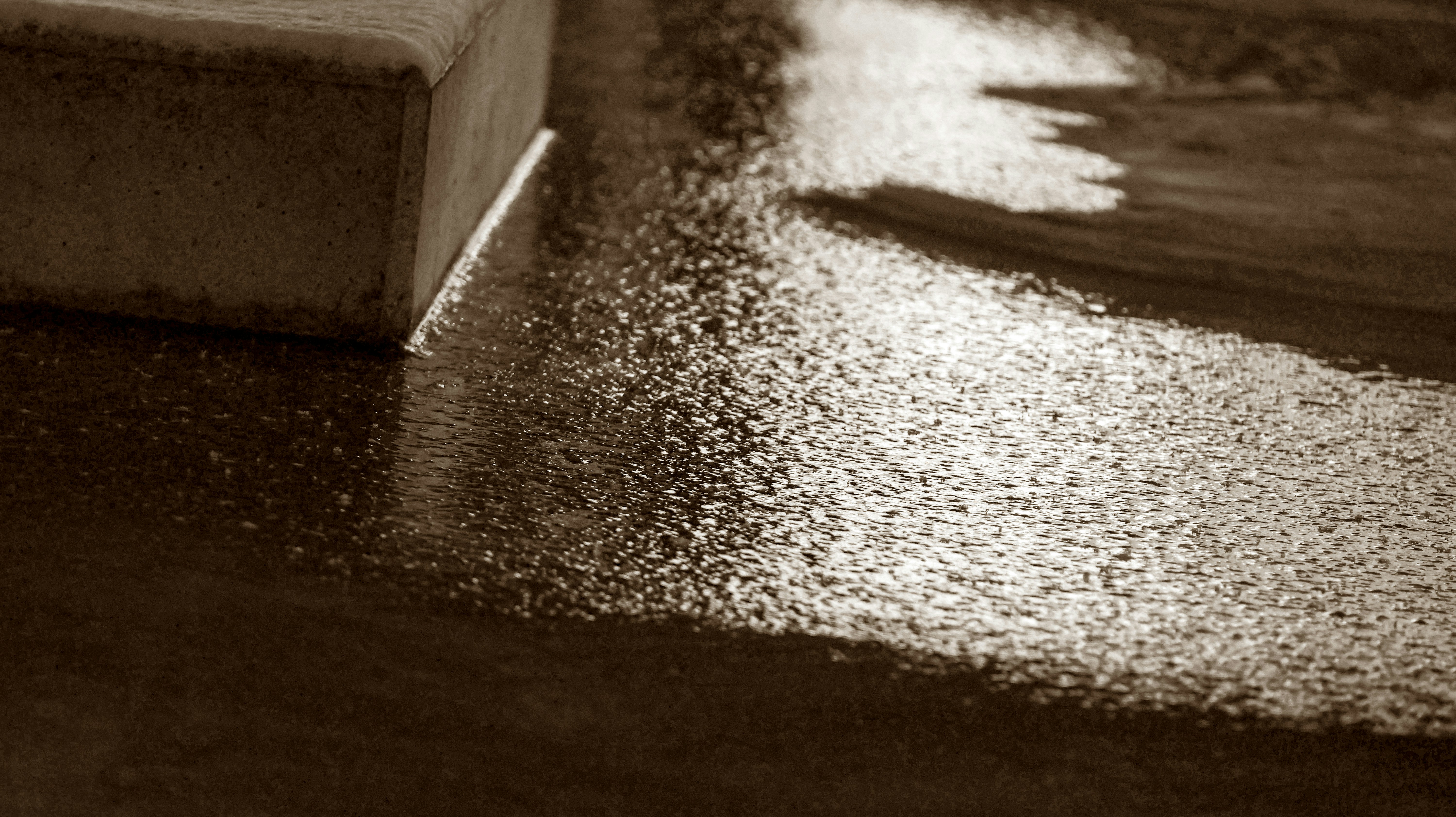 Person power washing a concrete driveway in daylight