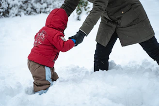 a man holding a child's hand in the snow