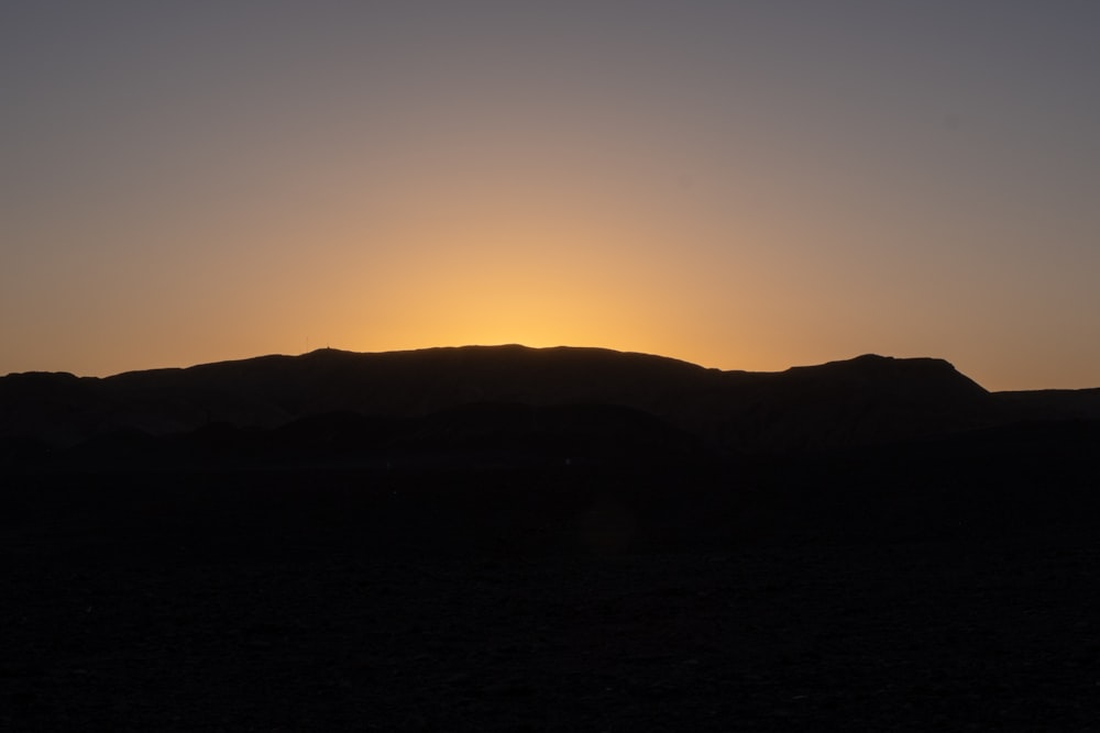 the sun is setting over a mountain range