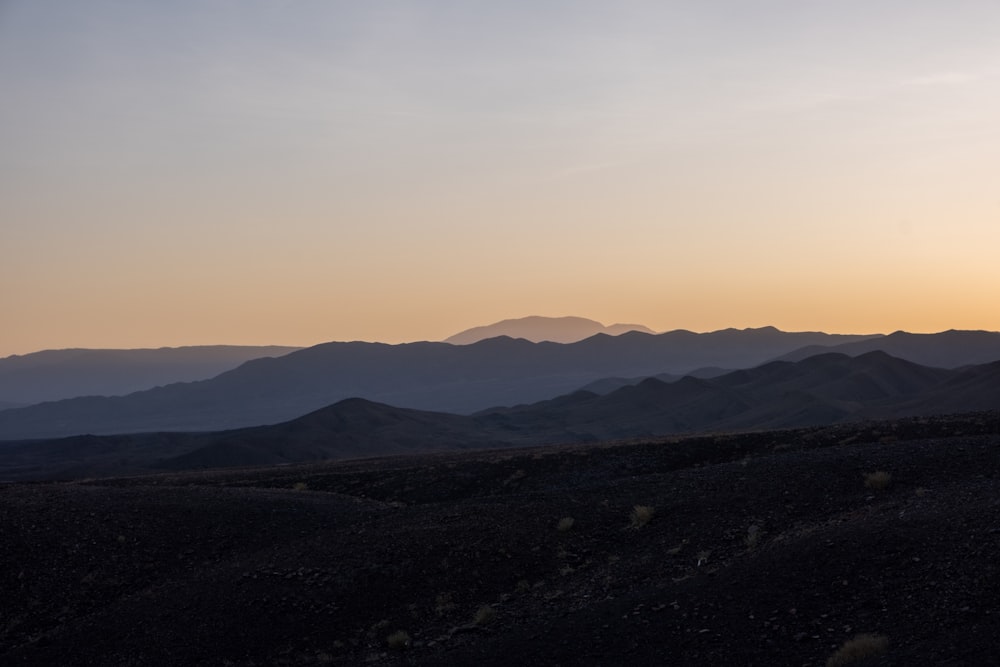 the sun is setting over a mountain range