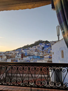 A bright, modern apartment balcony overlooking the turquoise waters of Saranda at sunset.