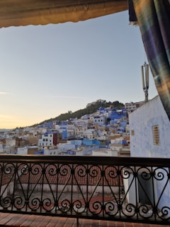 Balcony view at sunset with terracotta rooftops and the sea in the distance.