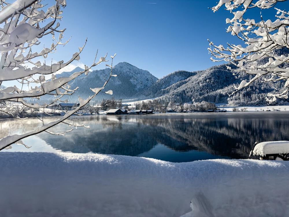 a lake surrounded by snow covered trees and mountains