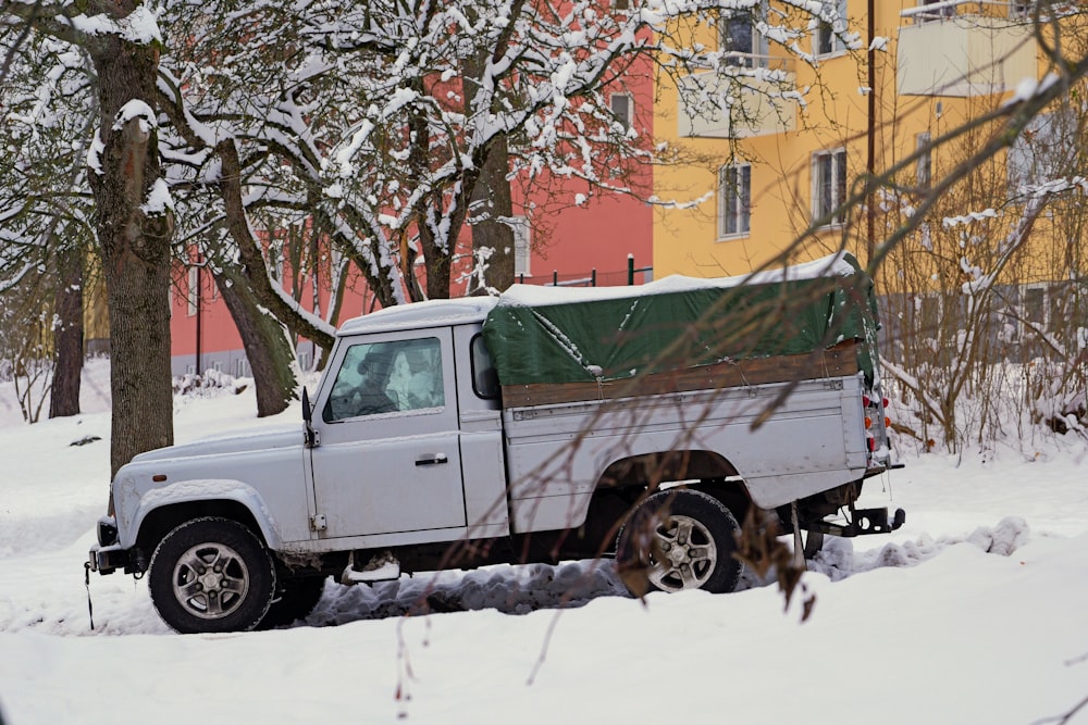 a white truck parked in the snow next to a tree