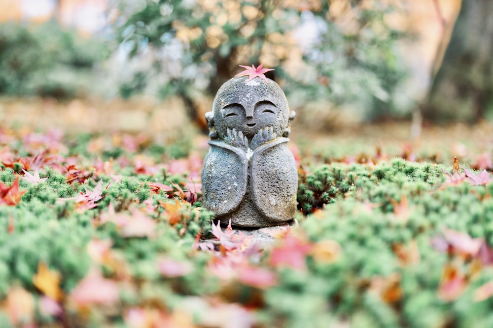 a small statue of a person sitting in a field of leaves