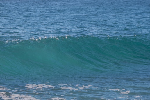 A serene wave gently rolling onto a calm beach at sunrise, symbolizing balance and flow.