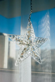 A sparkling suncatcher shaped like a star, glowing against a backdrop of green foliage.