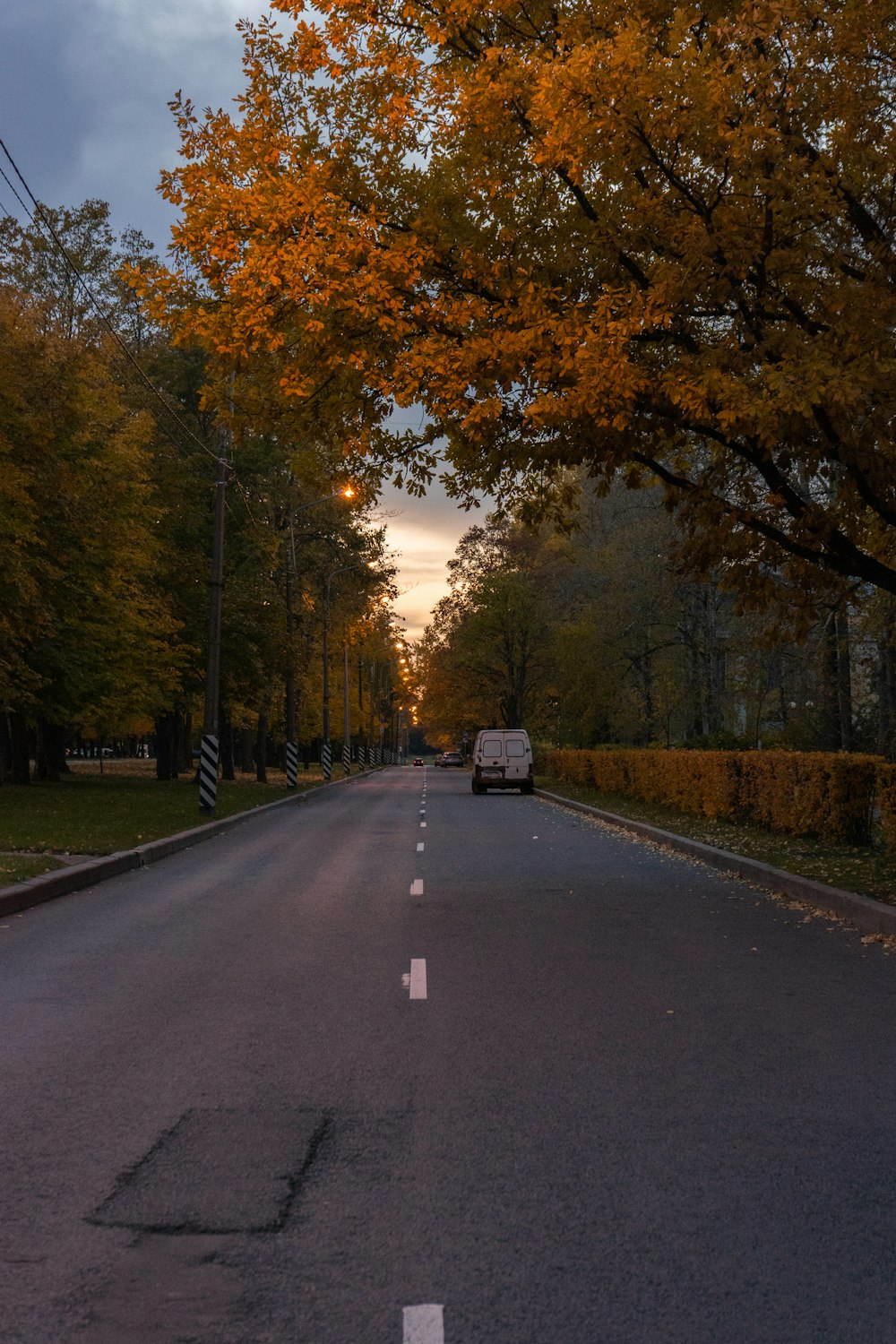 a van is driving down a tree lined street