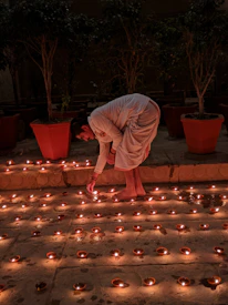A close-up of hands lighting traditional oil lamps during a festival evening.