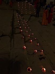 Pilgrims walking barefoot along an ancient stone path lined with flickering oil lamps.