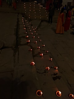 Pilgrims walking barefoot along an ancient stone path lined with flickering oil lamps.