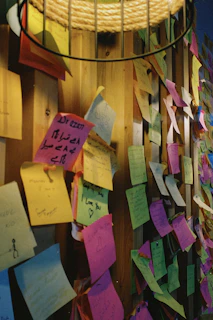 A wall filled with pinned poems, quotes, and creative ideas in a warm light
