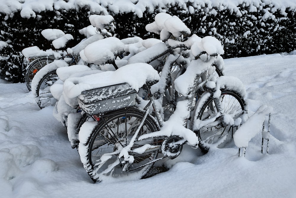 a bicycle covered in snow next to a bush