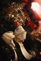 Christmas tree decorated with golden lights, red ribbons, and natural foliage