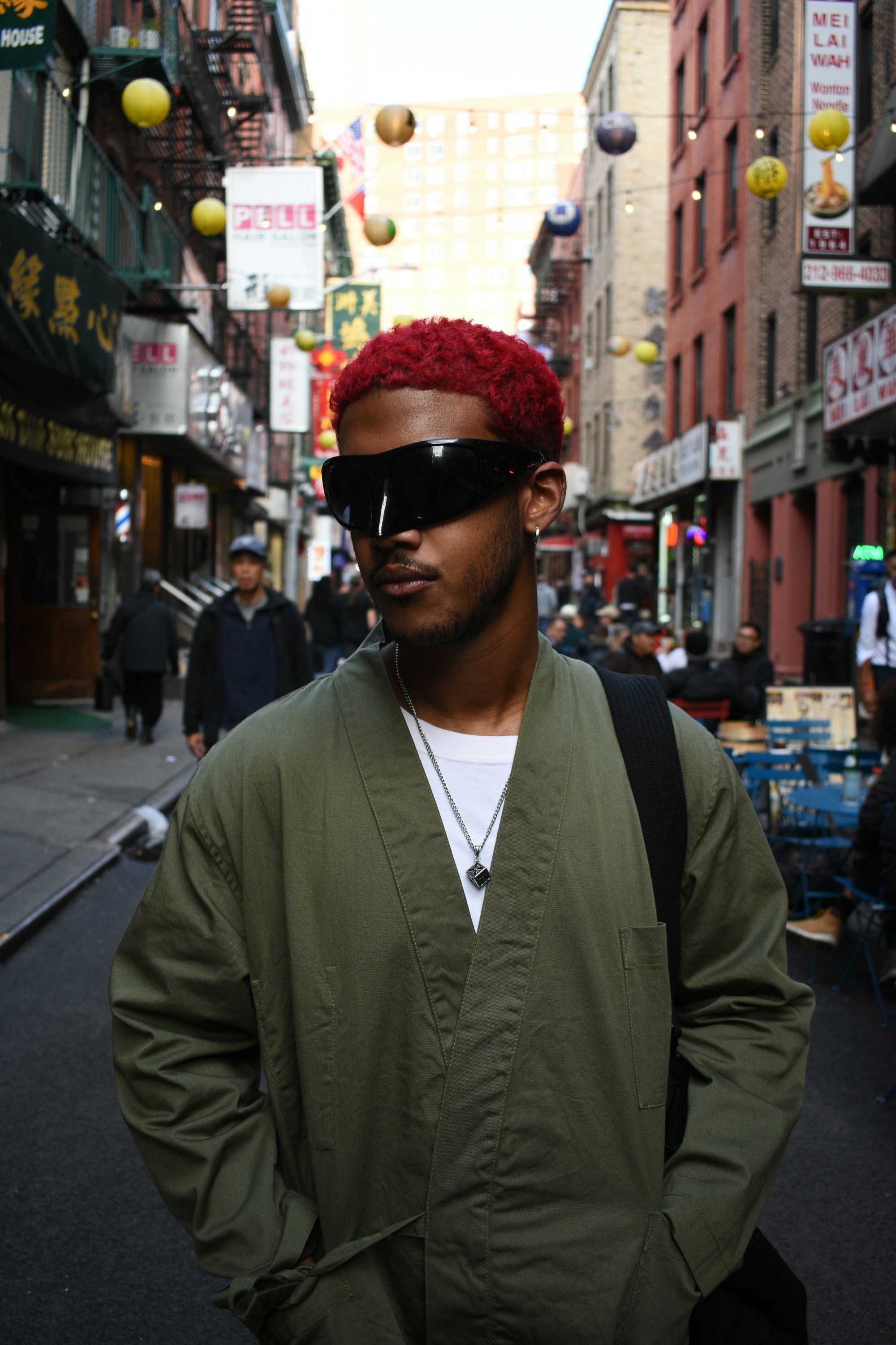 A man with a red hat and sunglasses standing in the middle of a street ...