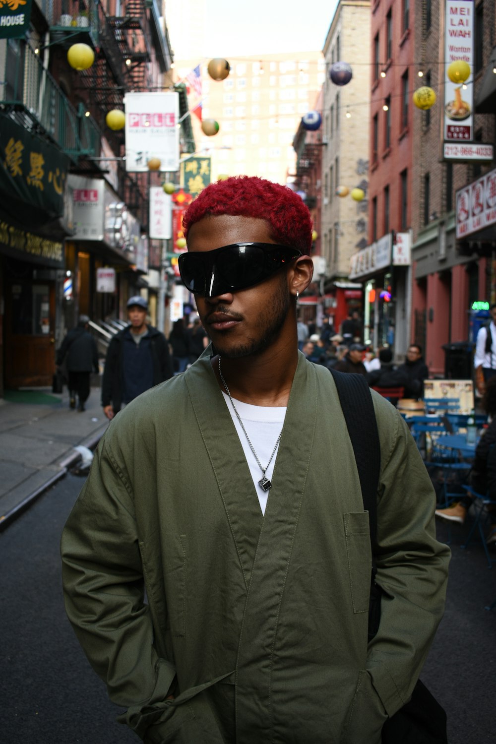 a man with a red hat and sunglasses standing in the middle of a street