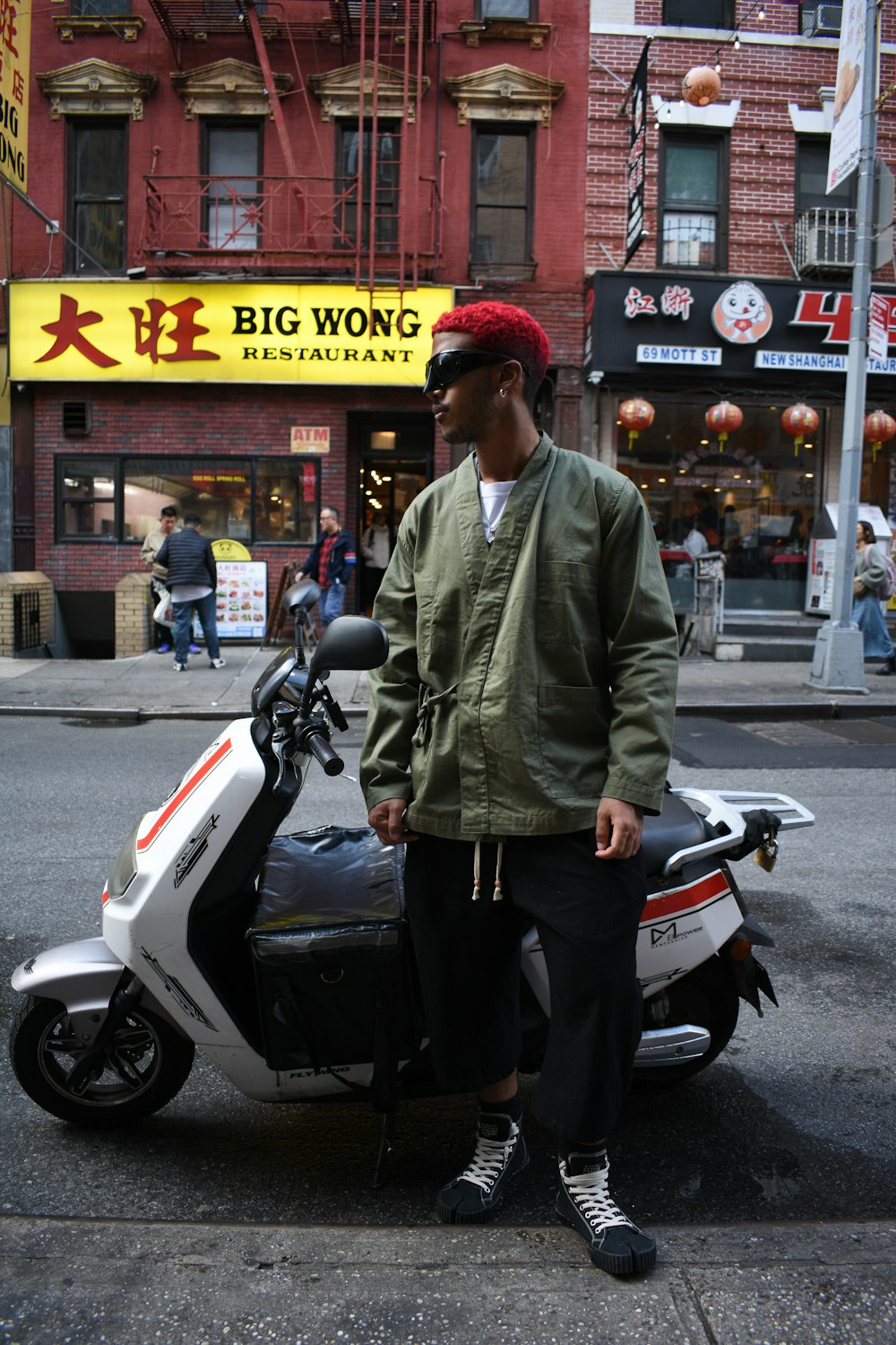a man standing next to a scooter on a city street