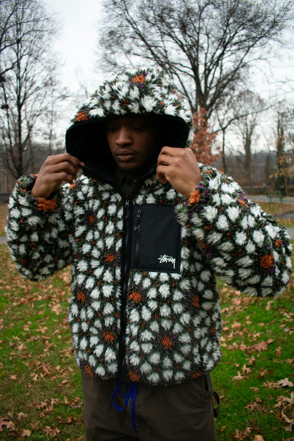 a man is standing in a park wearing a jacket