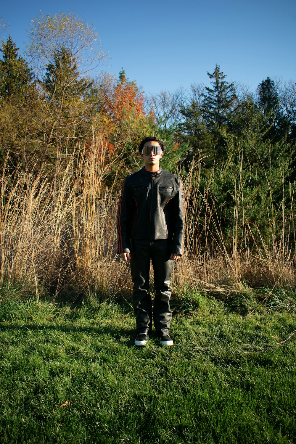 a man standing in a grassy field with trees in the background