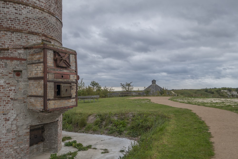 an old brick tower next to a dirt road