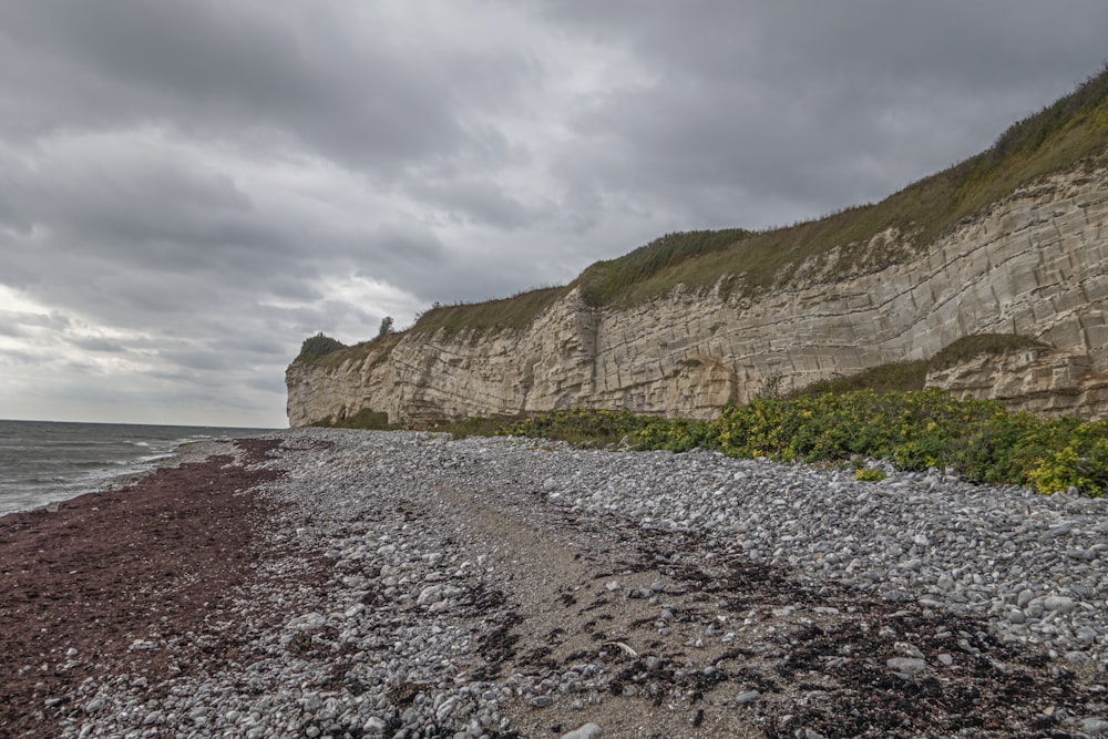 a rocky beach next to the ocean under a cloudy sky