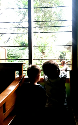 Parents watching their children play through a large glass window from the dining area.