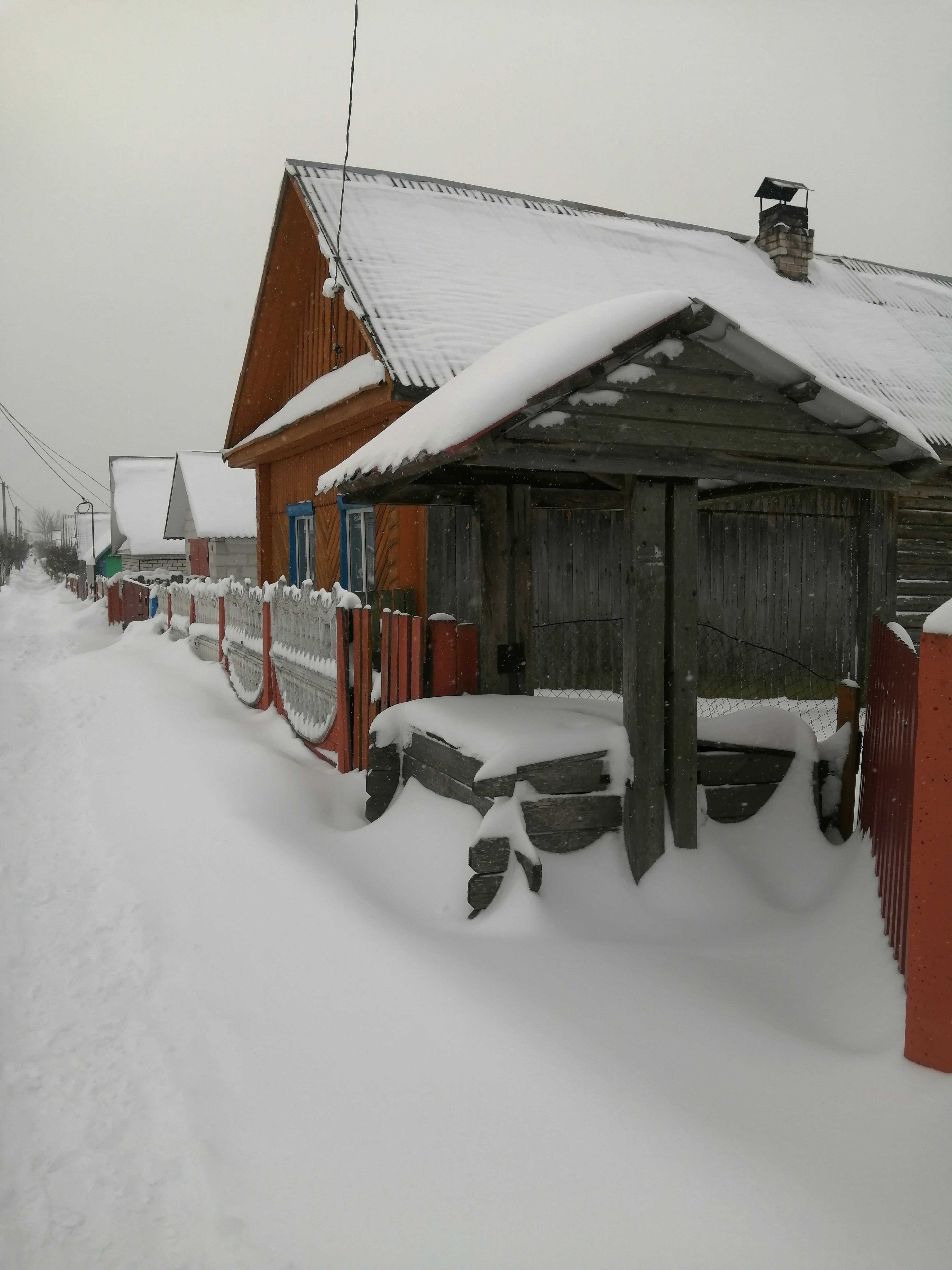 a snow covered road next to a red building