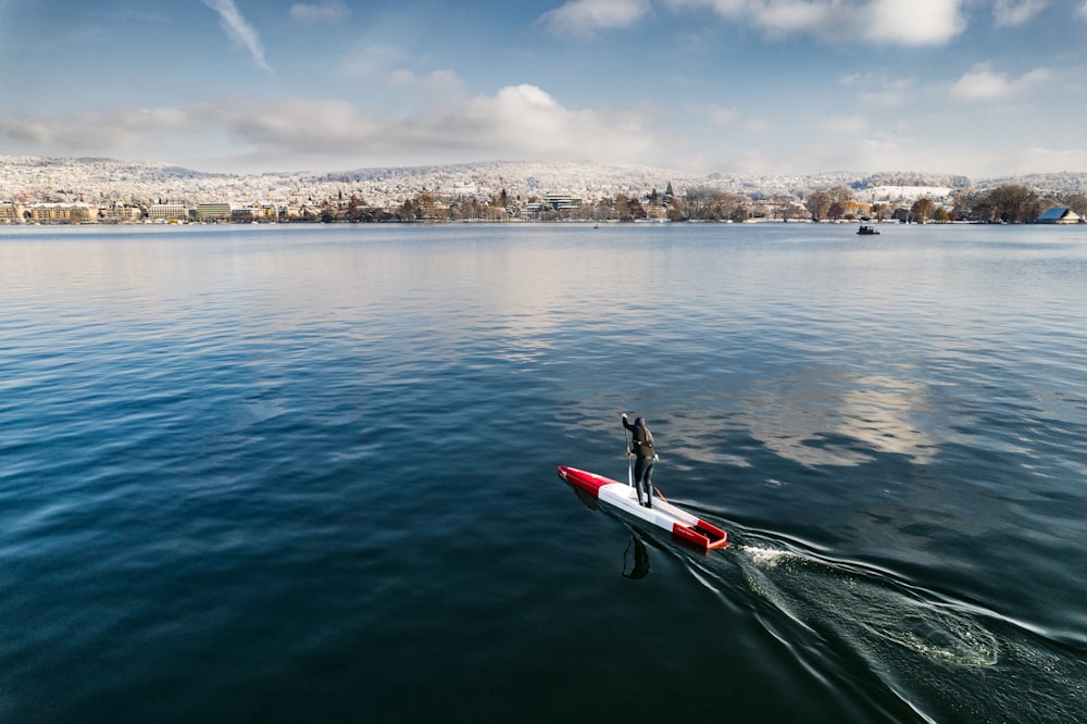 un uomo in piedi su una barca in mezzo a un lago