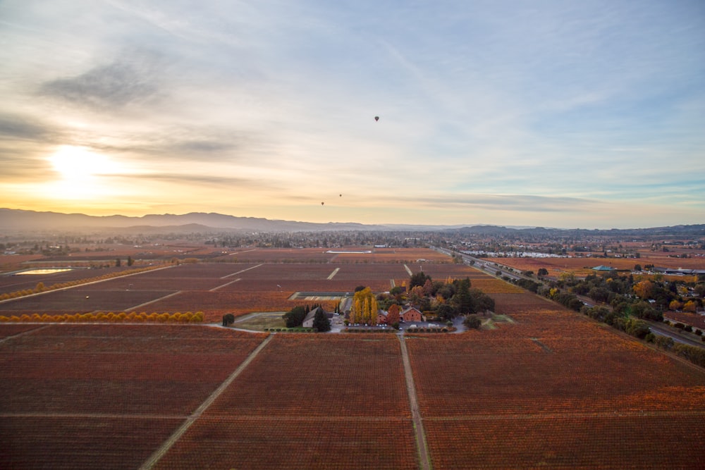 an aerial view of a field with a hot air balloon in the sky