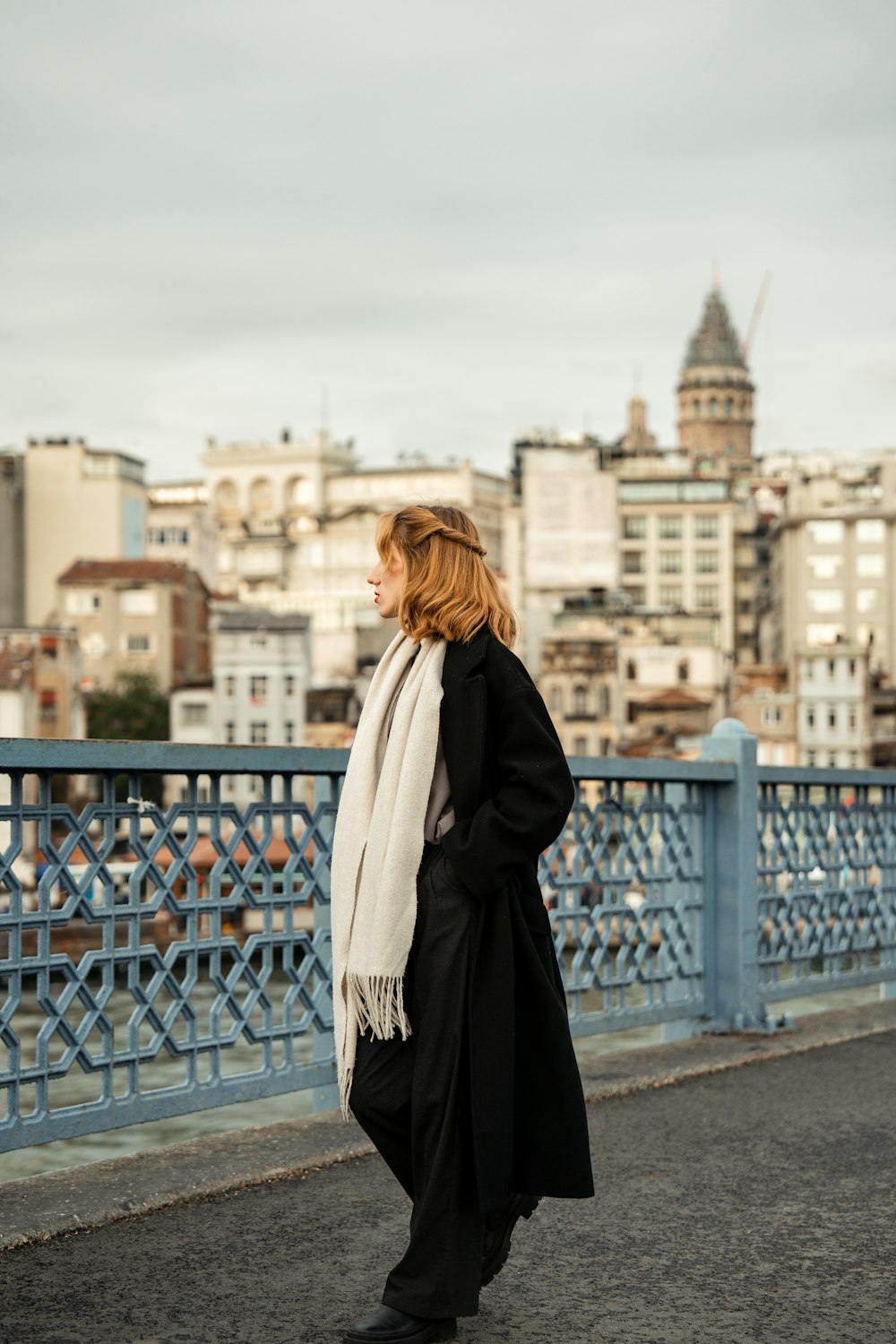 a woman walking across a bridge with a city in the background