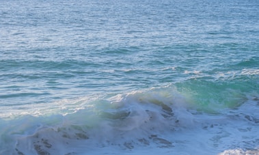 A sunlit beach with turquoise waves gently rolling onto white sand.