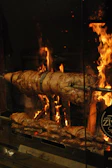 Traditional rotisserie spit turning slowly over glowing coals in a Normandy kitchen