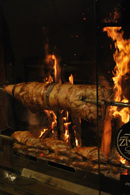 Traditional rotisserie spit turning slowly over glowing coals in a Normandy kitchen