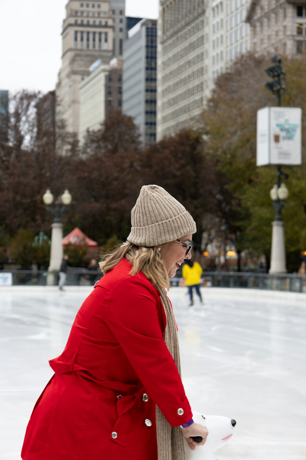 a woman in a red coat skating on an ice rink