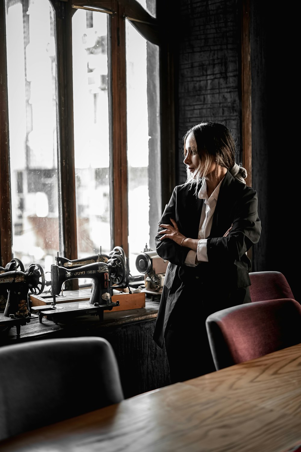 a woman standing in front of a window next to a sewing machine