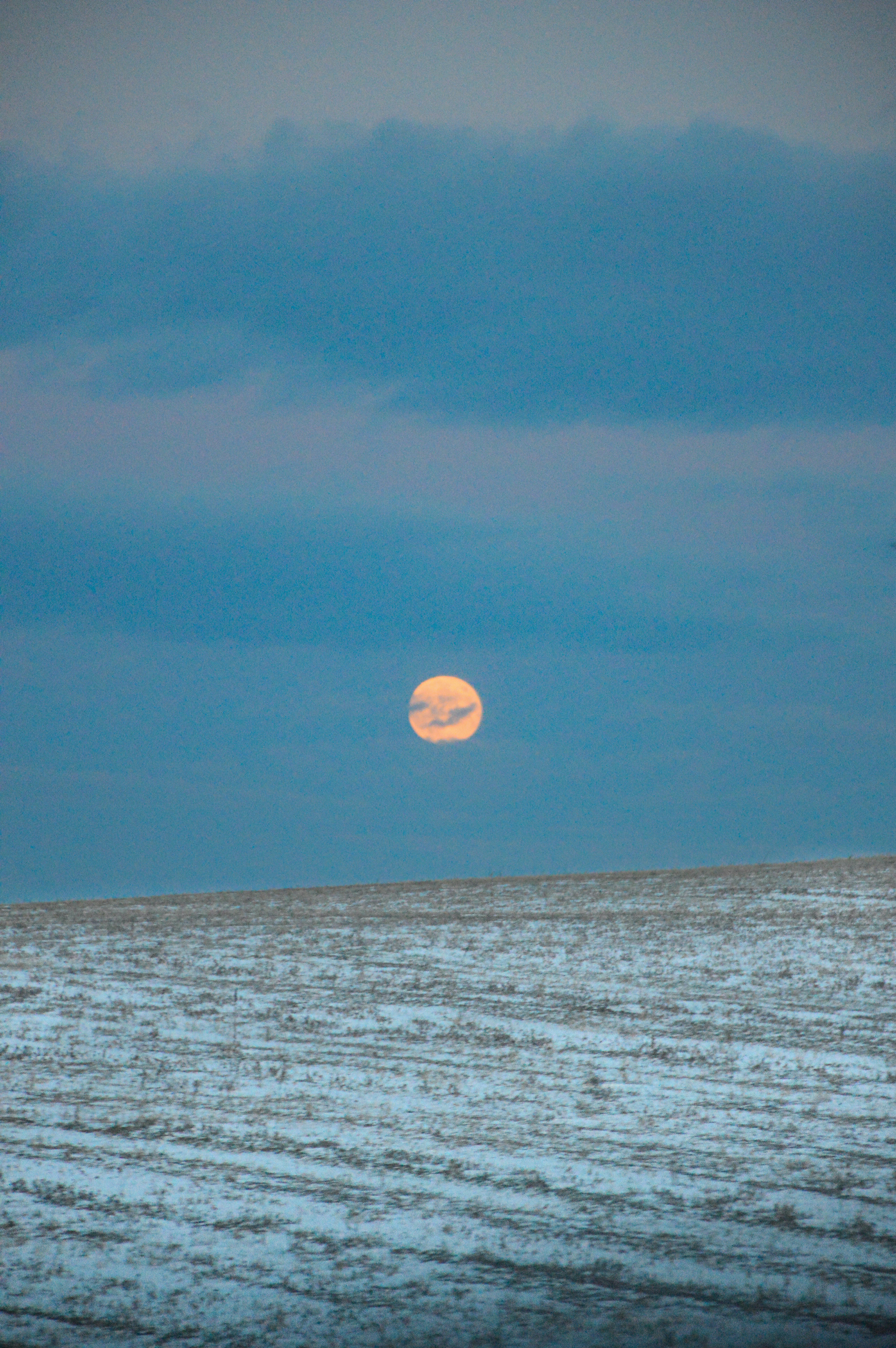 a full moon rising over a body of water