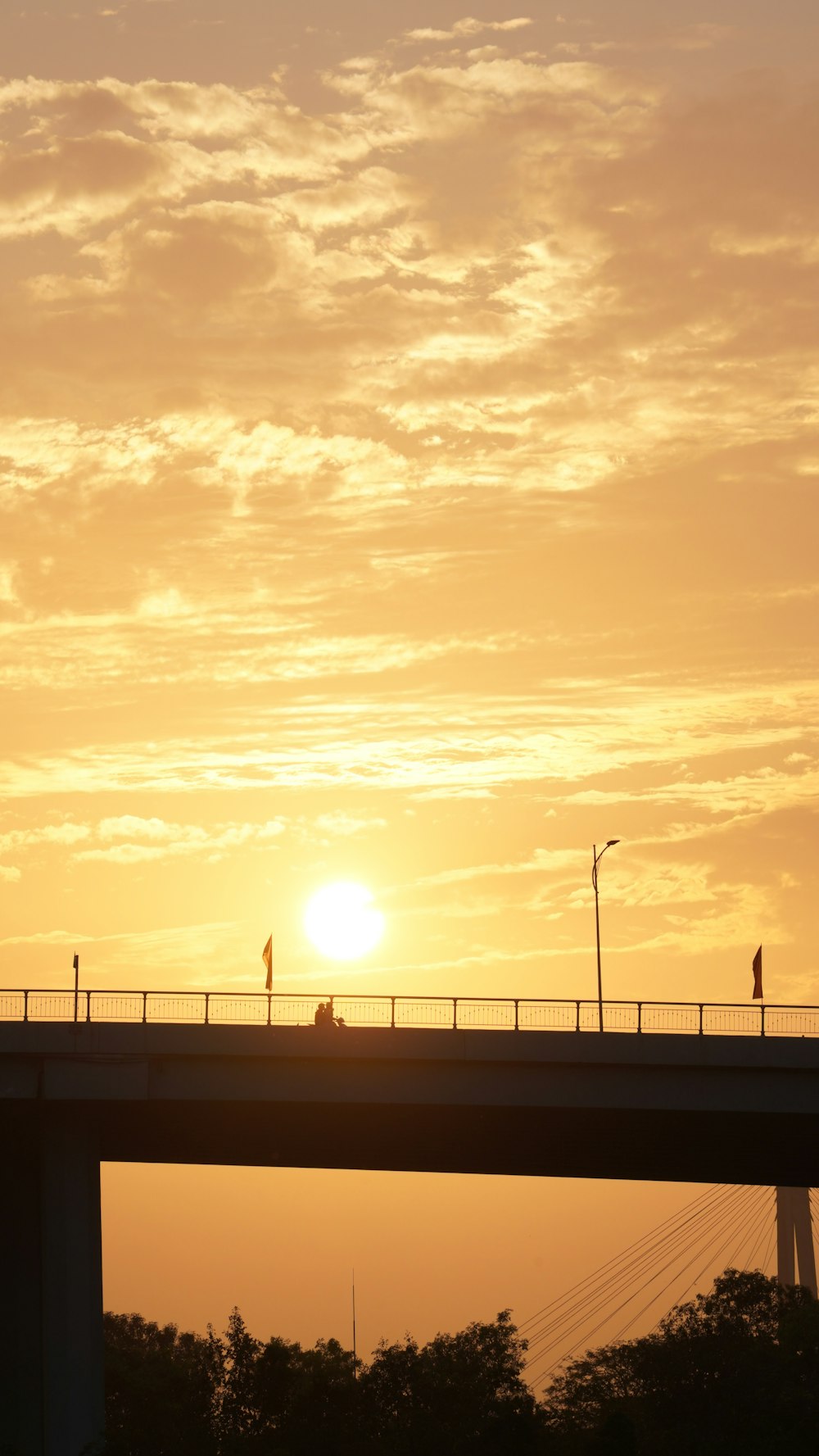 the sun is setting over a bridge with a traffic light