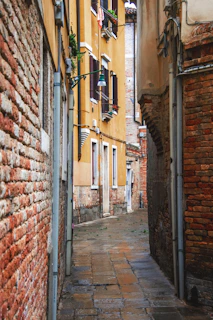 A quiet cobblestone alley in Lisbon bathed in golden afternoon light, with laundry hanging overhead