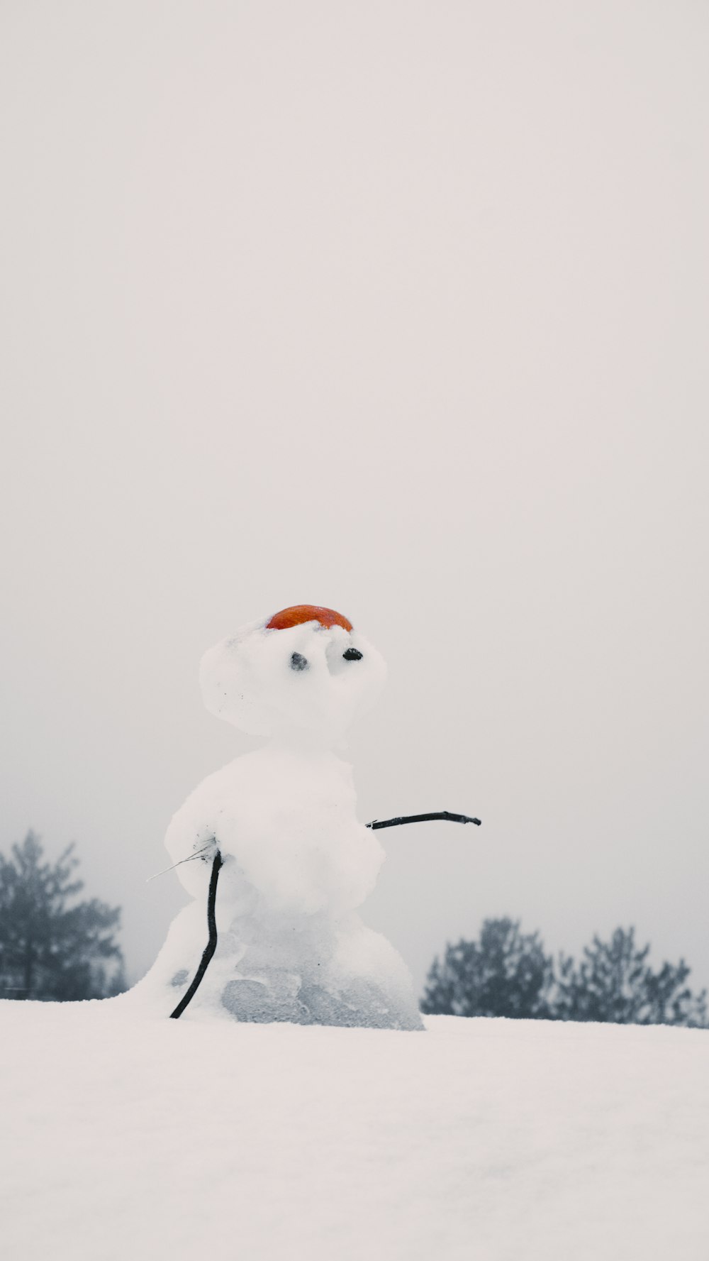 Um boneco de neve com um chapéu vermelho está na neve