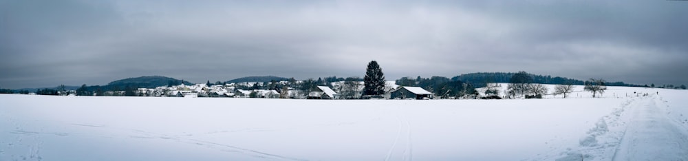 a snow covered field with a house in the distance