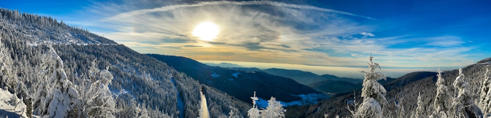 the sun is shining over a snowy mountain range