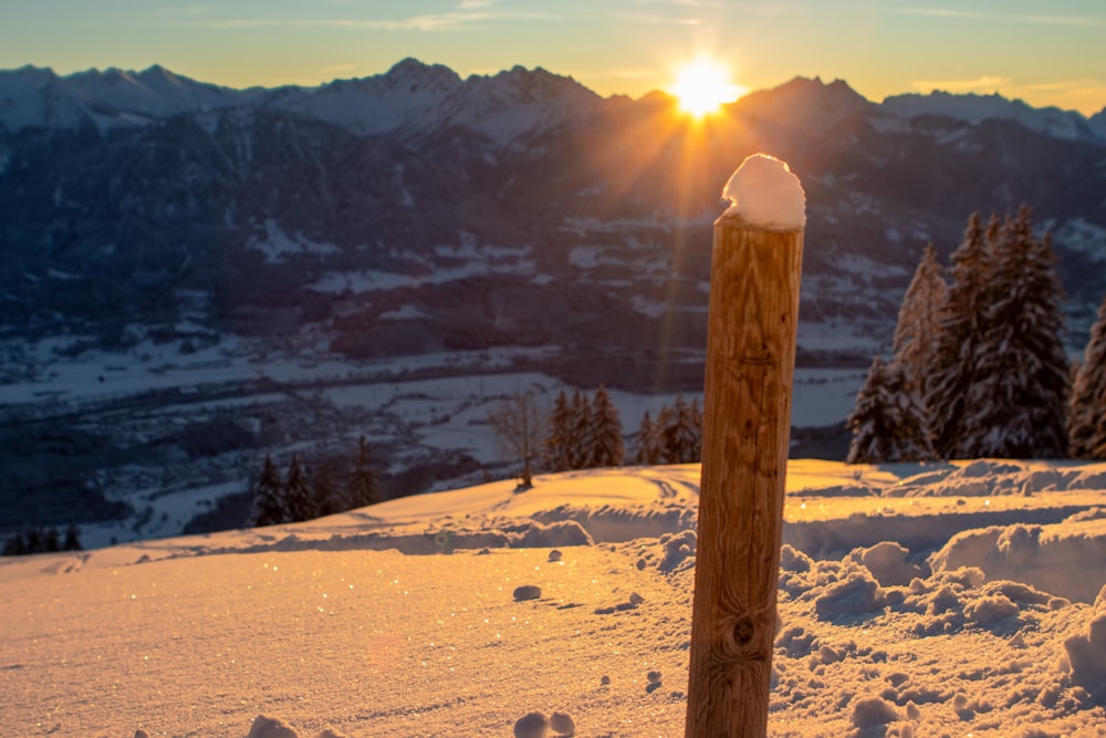 the sun is setting over a snowy mountain